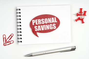On the table there are stationery, a notebook and a red sign with the inscription - Personal Savings