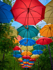Fototapeta na wymiar Decorative design of the canopy over the path in the form of opened colorful colored umbrellas
