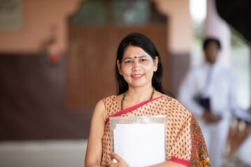 smiling portrait of Indian teacher in School background