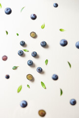 Concept flat lay with a  few juicy blueberries levitation with green leaves on yellow background. Top  view and close up