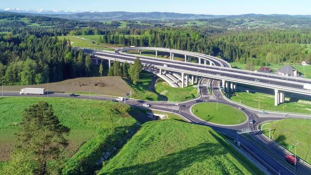New highway in Poland on national road no 7, E77, called Zakopianka.  Overpass junction with a traffic circle, viaducts, slip roads, cars near Skomielna Biala. Aerial view. Far view of Tatra Mountains