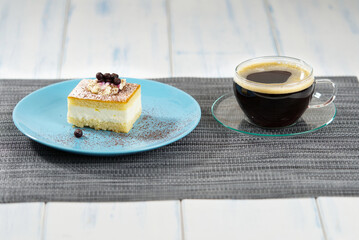 A piece of cake on a blue plate and a cup of coffee.
