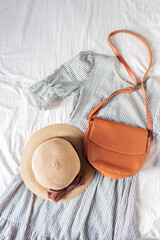 Beauty fashion flat lay with women's dress, a purse, brown shoes, a dried flower bouquet and sunglasses on white cotton cloth.  Top view fashion blog lifestyle concept.