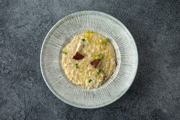 Risotto in a creamy sauce with mushrooms and parmesan. Ready menu for the restaurant. Neutral gray blue textured background