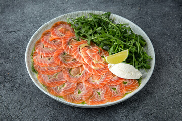 Salmon carpaccio with cheese and arugula. Ready menu for the restaurant. Gray blue textured...