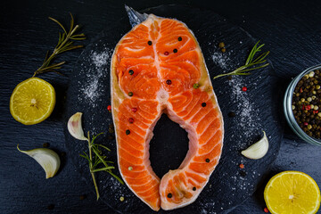 Raw salmon steak and spices on a slate board. Top view