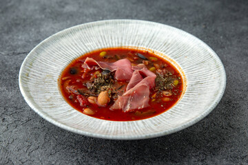 First course. Mexican soup with beans and prosciutto. Ready menu for the restaurant. Neutral gray blue textured background