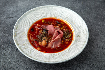 First course. Mexican soup with beans and prosciutto. Ready menu for the restaurant. Neutral gray blue textured background