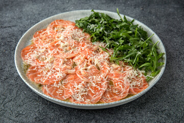 Salmon carpaccio with cheese and arugula. Ready menu for the restaurant. Gray blue textured background
