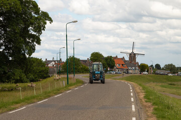 Tractor drives away over the narrow dike of the picturesque fortified town of Wijk van Duurstede, the Netherlands.