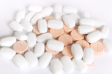 White and colored pills on a white background. Oblong and round pills close-up. Healthcare and medicine.	