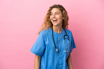 Young surgeon doctor woman isolated on pink background looking to the side and smiling