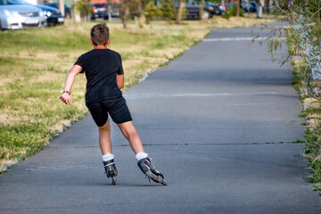 A sporting, athletic boy roller skating in a park on a summer day.