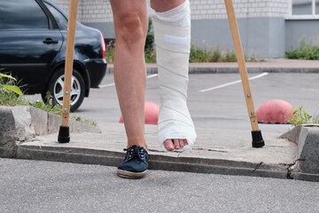 A woman with a broken leg overcomes an obstacle with crutches
