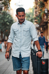 Portrait of a dark-haired Latin boy posing for a photo session on a street in the city of Barcelona..