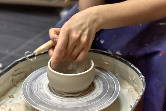 The hands of the master ceramist with a special tool align the almost finished cup on the potter's wheel