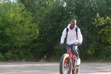 Naklejka premium A young African-American man rides a bicycle in nature