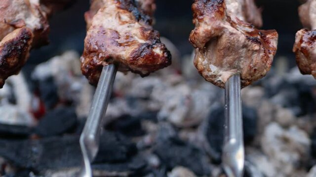 Pork meat on metal skewers. Barbecue with coals for cooking baked food in the fresh air. Outdoor, the backyard of the house. fatty meat is fried on a fire, dripping juice. close up