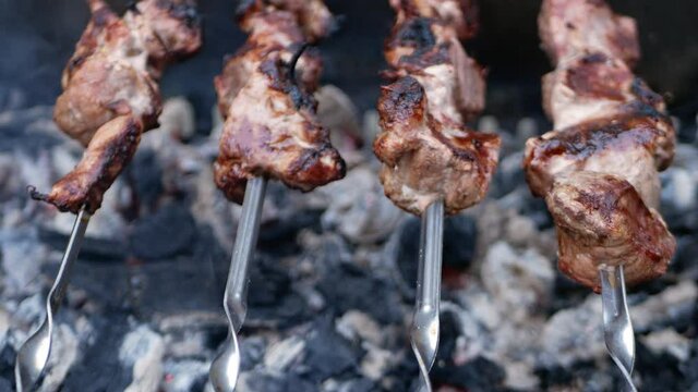 Pork meat on metal skewers. Barbecue with coals for cooking baked food in the fresh air. Outdoor, the backyard of the house. fatty meat is fried on a fire, dripping juice. slide way