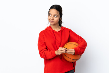 Young woman playing basketball over isolated white background scheming something