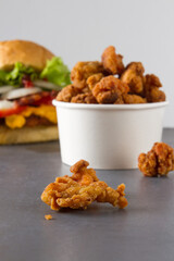chicken nuggets crispy fries, white bucket, and a burger background
