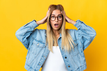 Young blonde woman isolated on yellow background with surprise expression