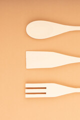 Three wooden spatulas for the kitchen on a light peach background. Bamboo kitchen tools.