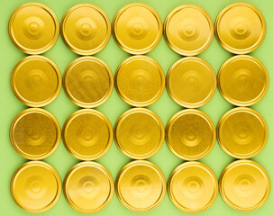 Lids for jars of gold color top view on a green background.