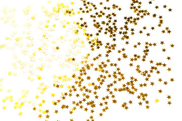 Gold sequins in the shape of stars shimmer on a white background. Backgrounds with copyspace for a holiday, party decoration, Christmas and new year, birthday and anniversary. Gradient and texture