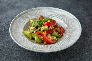 Hearty dietary salad made from tomatoes, avocado, pine nuts and sauce. Vegetarian food. Ready menu for the restaurant. Neutral gray blue textured background