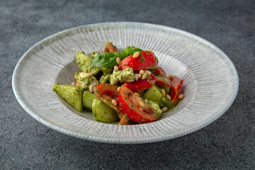 Hearty dietary salad made from tomatoes, avocado, pine nuts and sauce. Vegetarian food. Ready menu for the restaurant. Neutral gray blue textured background