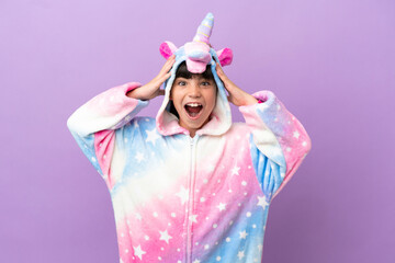 Little kid wearing a unicorn pajama isolated on purple background with surprise expression