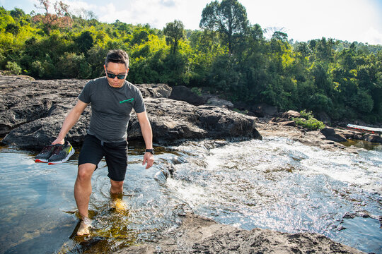 Man wading through Tatai river close to Tatai waterfall in Cambodia