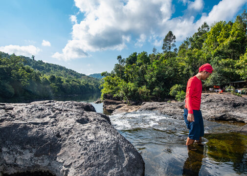 Man wading through Tatai river close to Tatai waterfall in Cambodia