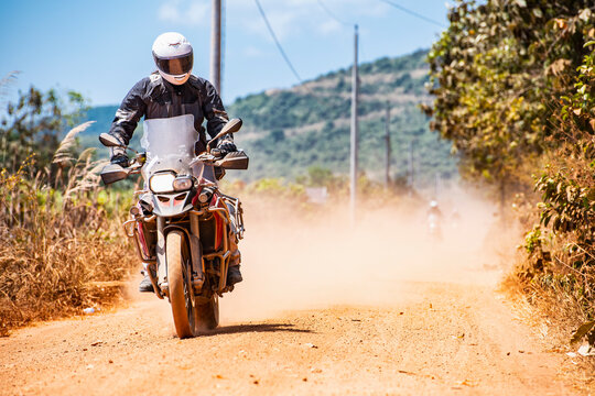 Man riding his adventure motorbike on dusty road in Cambodia
