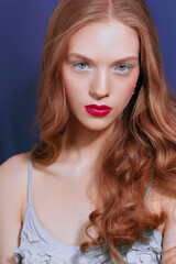Young woman with long red wavy hair, green eyeshadows, red lipstick.