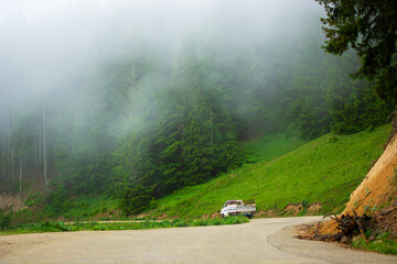 A pickup truck driving through the fog on a mountain road. © photohasan