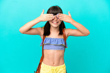 Little caucasian kid going to the beach isolated on blue background covering eyes by hands