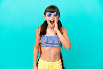 Little caucasian kid going to the beach isolated on blue background with surprise and shocked...