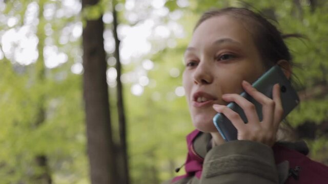 Asian woman talking on the phone on in a mountain forest.