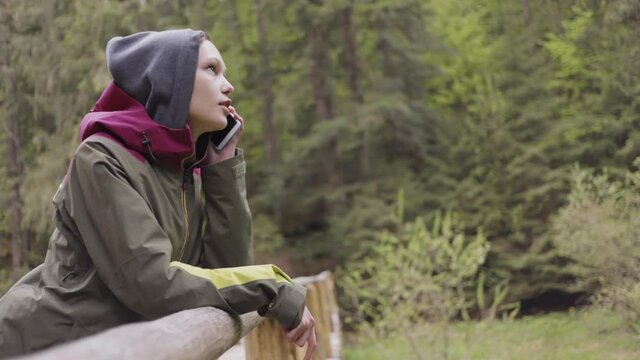 Asian woman talking on the phone on in a mountain forest.