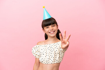 Little caucasian kid with birthday hat isolated on pink background happy and counting three with...