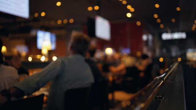 Group of people dringing and chatting in bar blurry footage