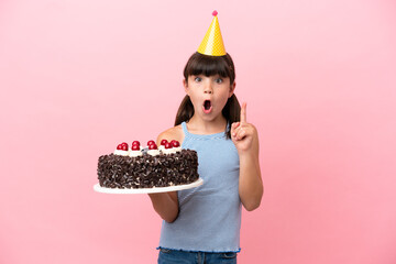 Little caucasian kid holding birthday cake isolated in pink background intending to realizes the...