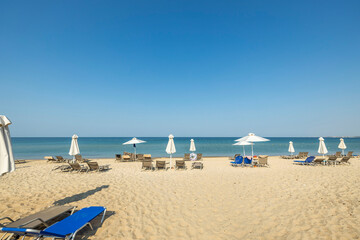 Fototapeta na wymiar Landscape view of empty sunbeds under umbrellas on sand beach. Greece. 