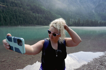 Lovely young adult woman fixes and primps her hair before taking a selfie after hiking Avalanche...
