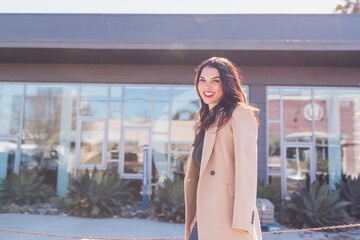 Business woman walking on the sidewalk with a big smile on her face.