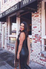 Smiling woman walking in front of restaurant with brick walls.