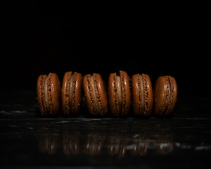 Line of Chocolate Salted Caramel Macarons on Black Marble