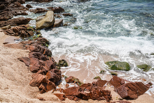 Image of a shore with rocks and sand on a Mediterranean beach